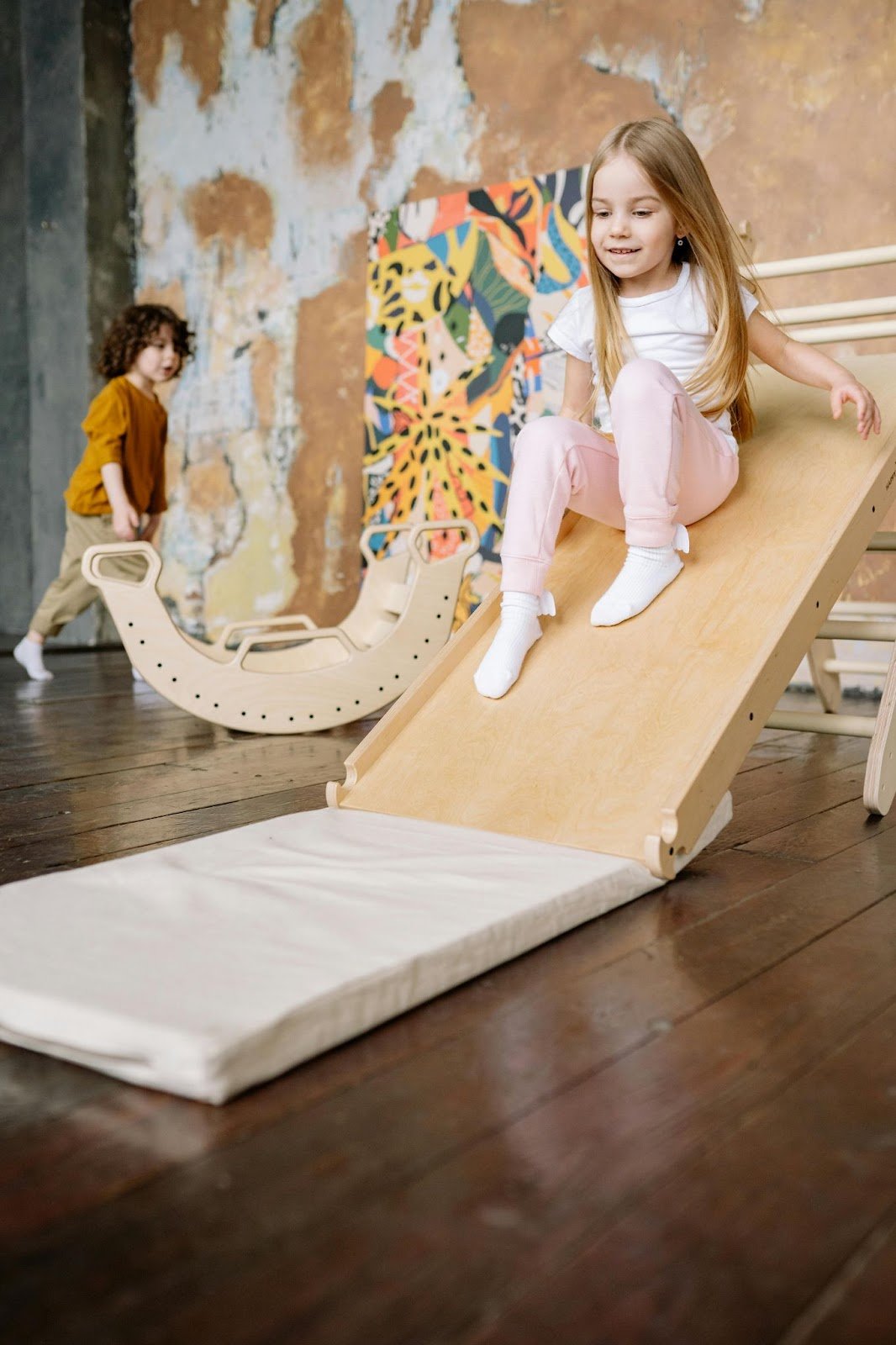 Girl playing on a wooden slide. This article covers safe and stylish play areas for kids.