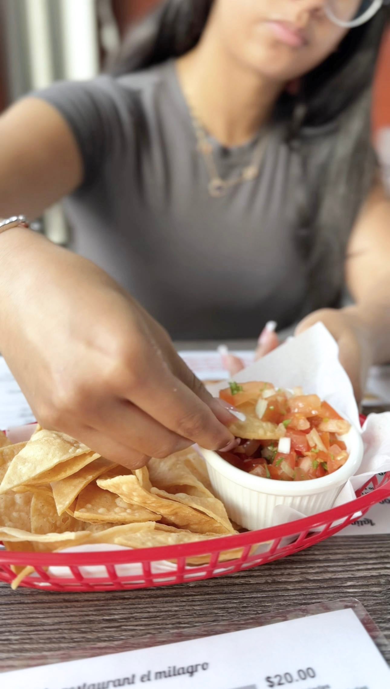 A girl eats chunky salsa at El Milagro Restaurant on Erie St.