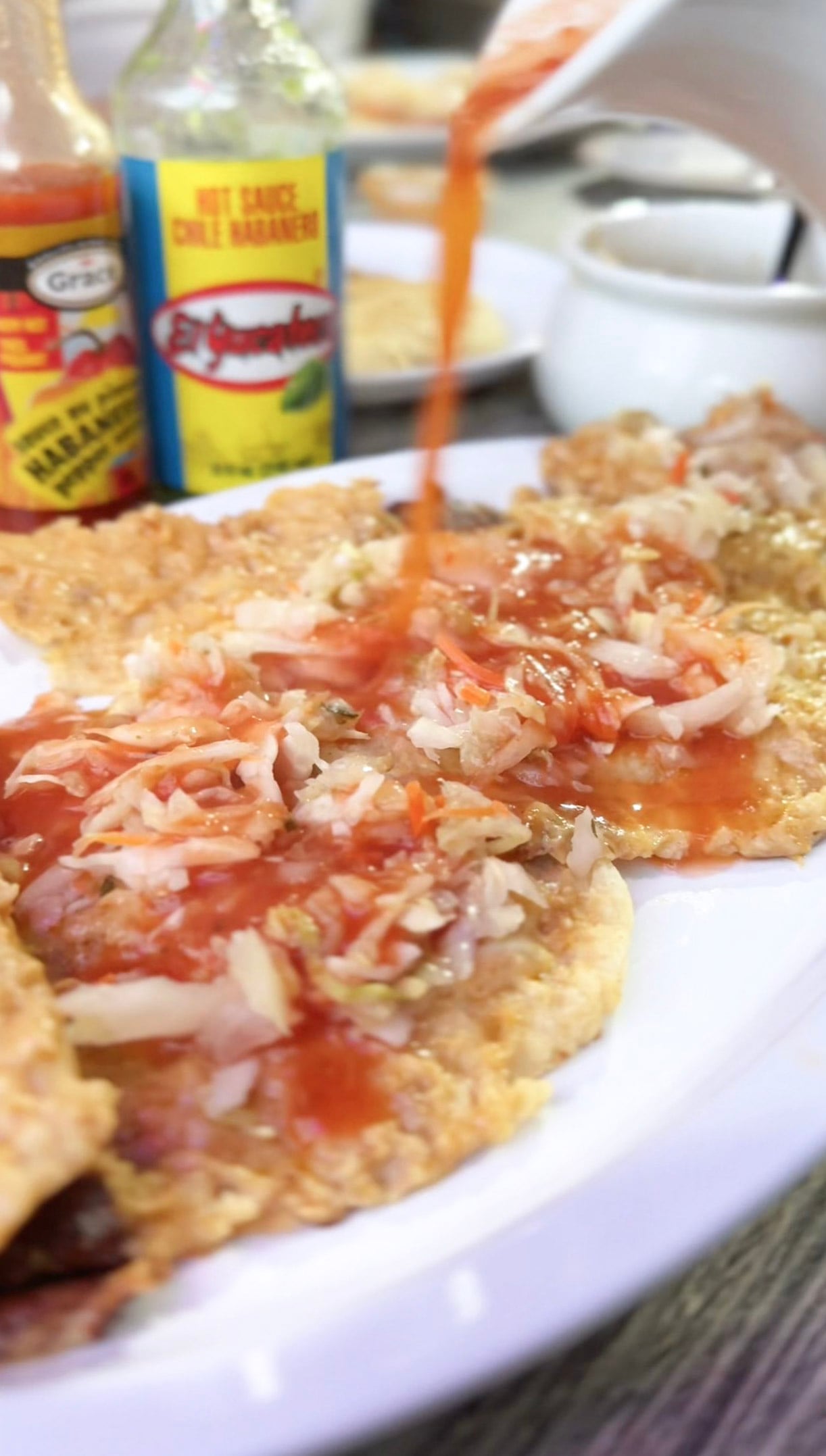Salsa is being poured on top of a pair of pupusas from El Milagro Restaurant.