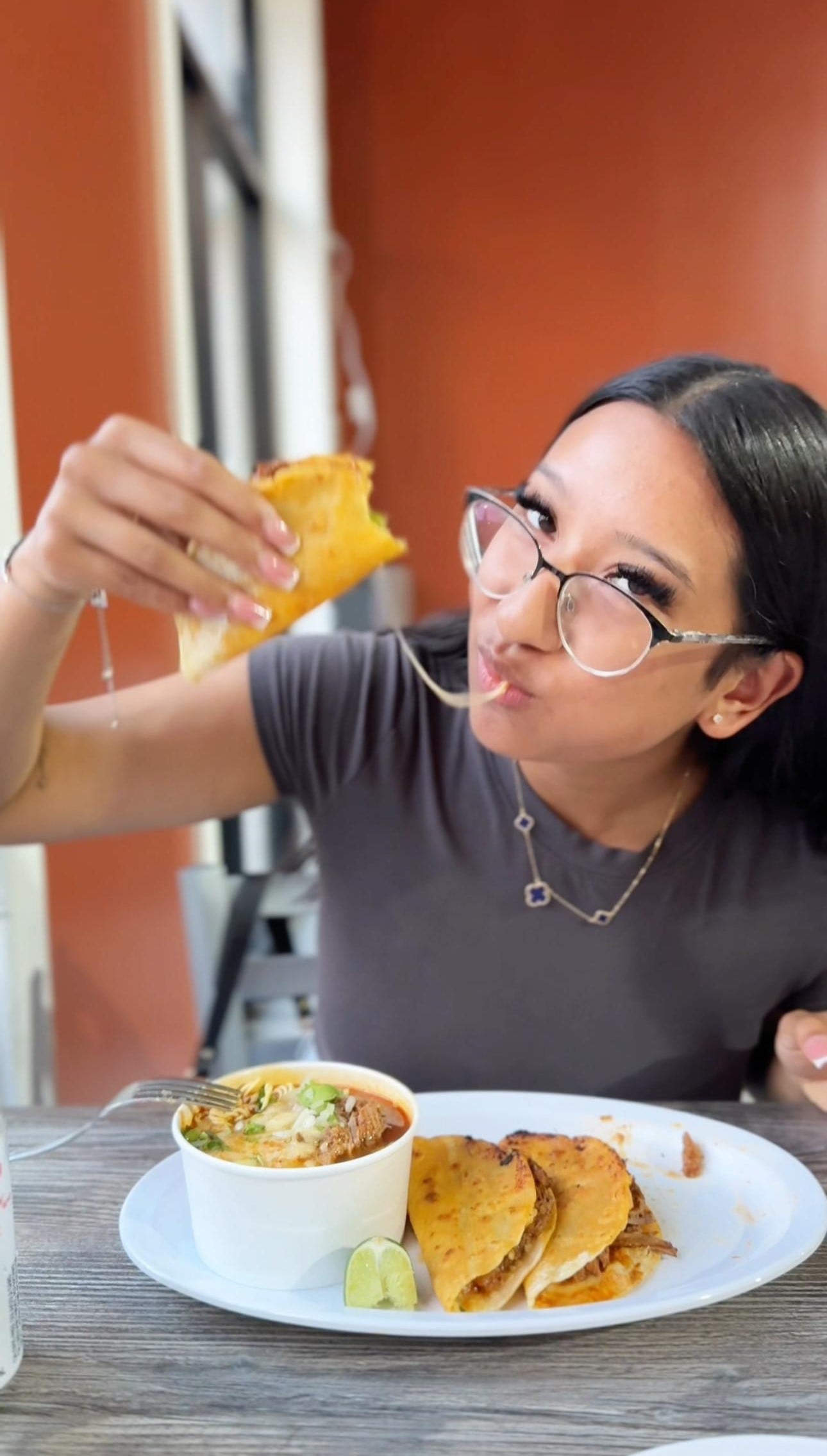 Gabby holds a birria taco with a cheese pull. This article covers where to eat pupusas and tacos in Windsor, ON.
