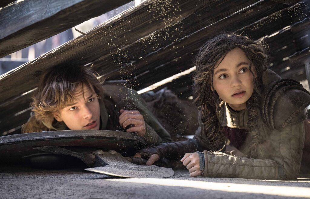 Hiccup and Astrid hide from dragons during training.