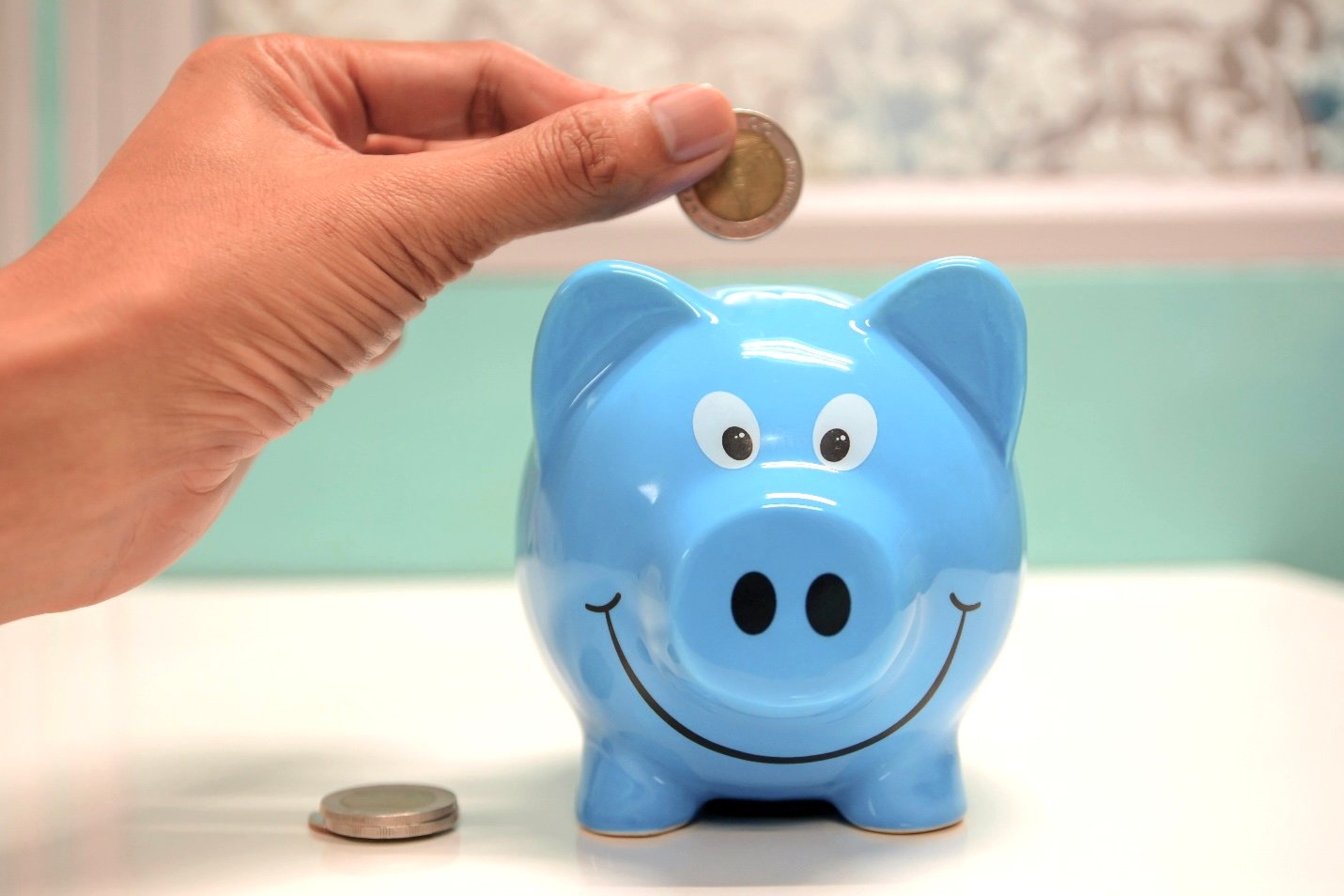 A woman inserts a coin into a blue piggy bank. This article covers how modern savers are thinking beyond traditional banks.