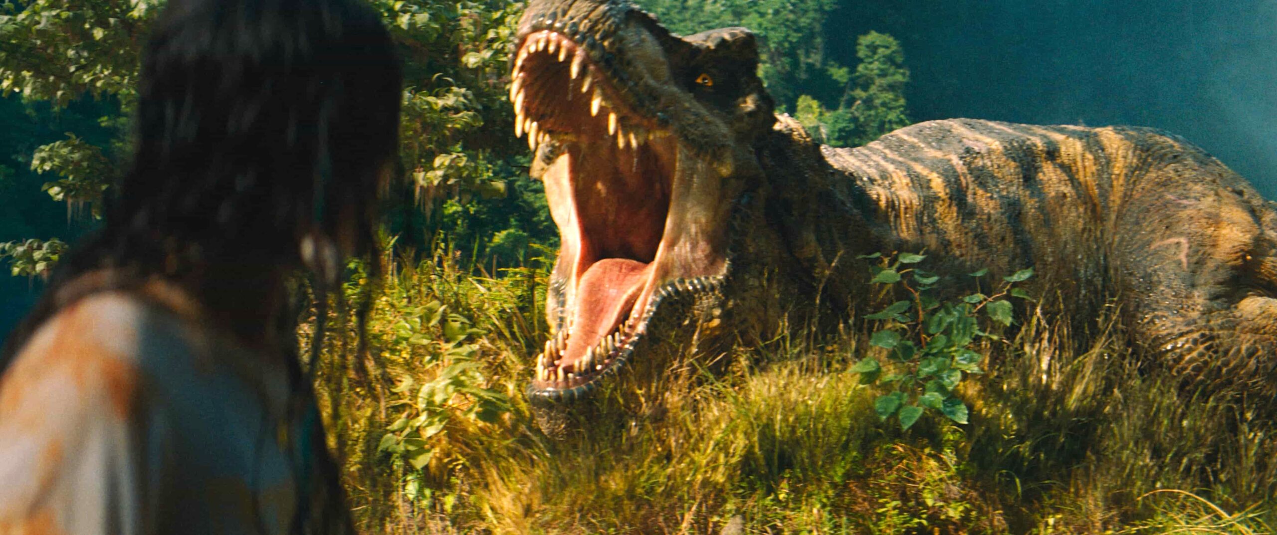 A girl stands in front of a dinosaur that is roaring. A scene from Jurassic World: Rebirth.