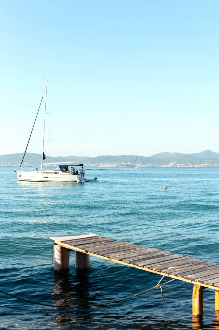 A beautiful seascape is shown in Croatia. There is a boat and a deck. This article covers what to expect on a Plitvice Tour from Zadar.