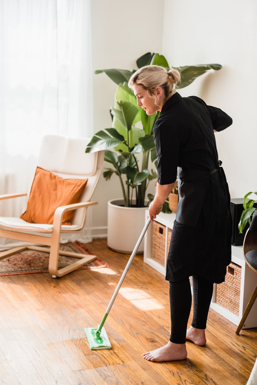 A woman sweeping a floor during the fall. This article covers why Fall home cleaning is the next big thing.