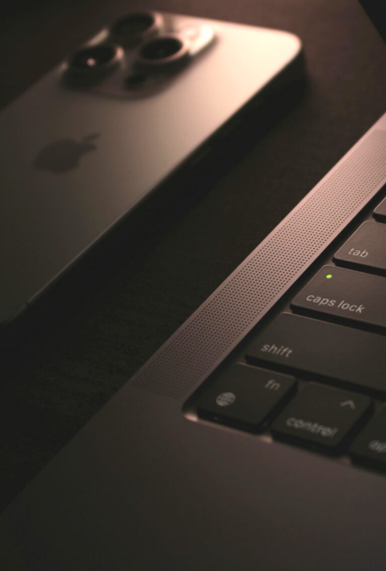 A dark and moody pictures of a close up of a laptop and iPhone. This article covers embracing digitalization in celebratory traditions.