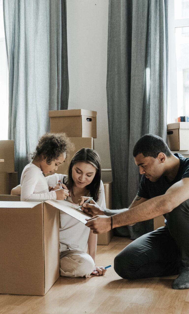 A family is surrounded by boxes and is unpacking from a move. This article covers how to create a cohesive home style after a big transition.
