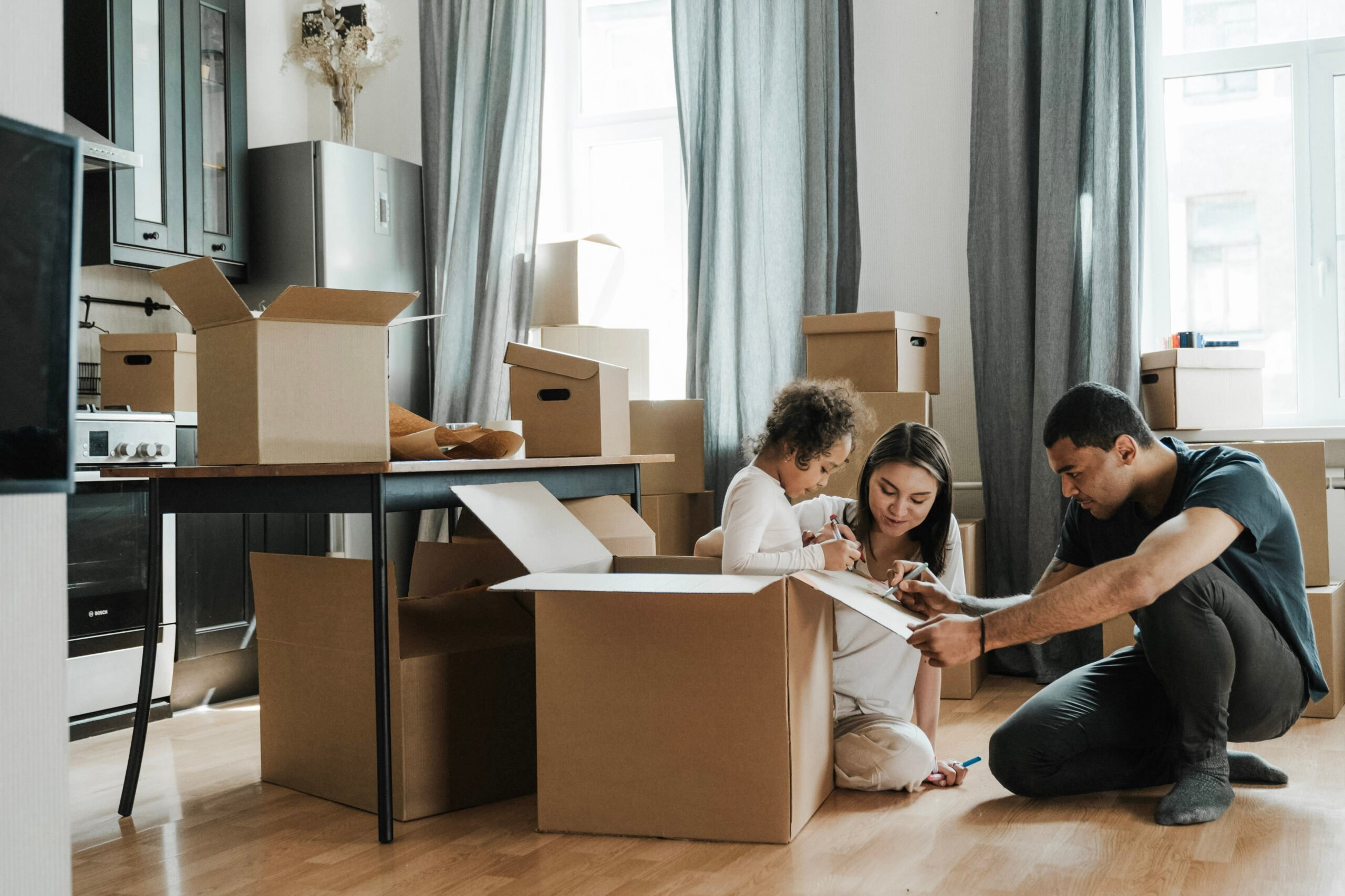A family is surrounded by boxes and is unpacking from a move. This article covers how to create a cohesive home style after a big transition.