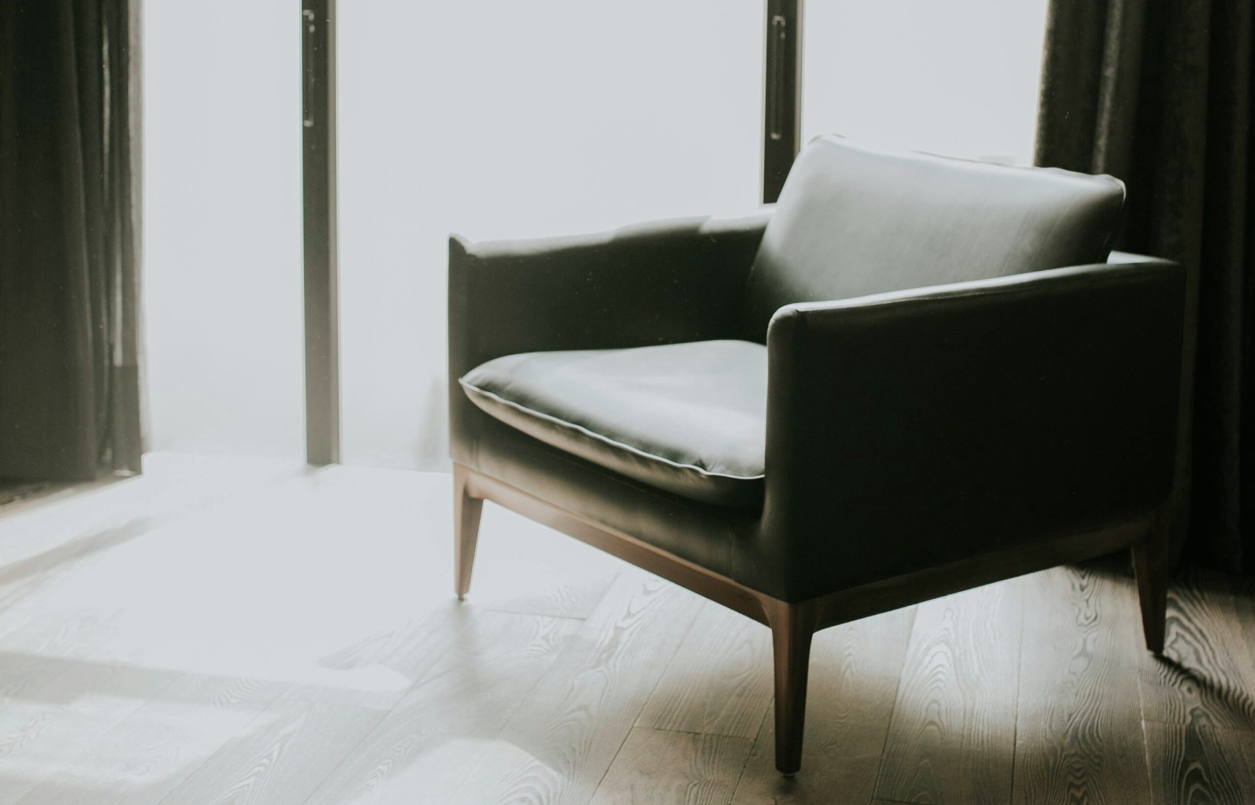 A mid-century modern style chair sits next to a window near a window with bright sun. This article covers how to protect your furniture from the sun.