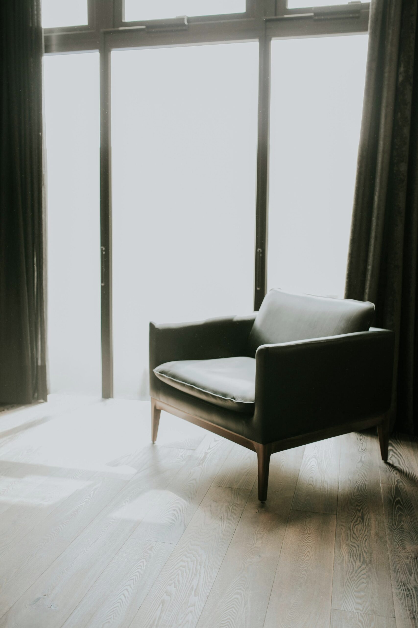A mid-century modern style chair sits next to a window near a window with bright sun. This article covers how to protect your furniture from the sun.
