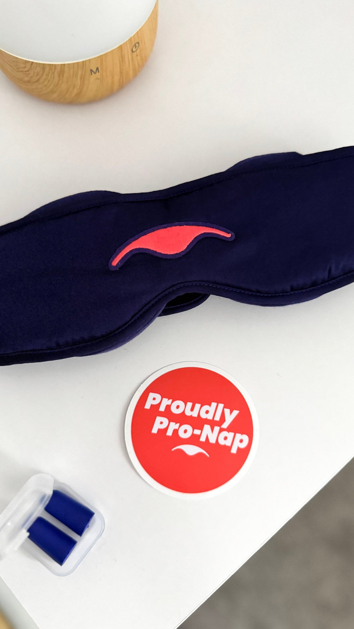 A Proudly Pro-Nap sticker with earplugs, diffuser, and Manta Silk Sleep Mask.