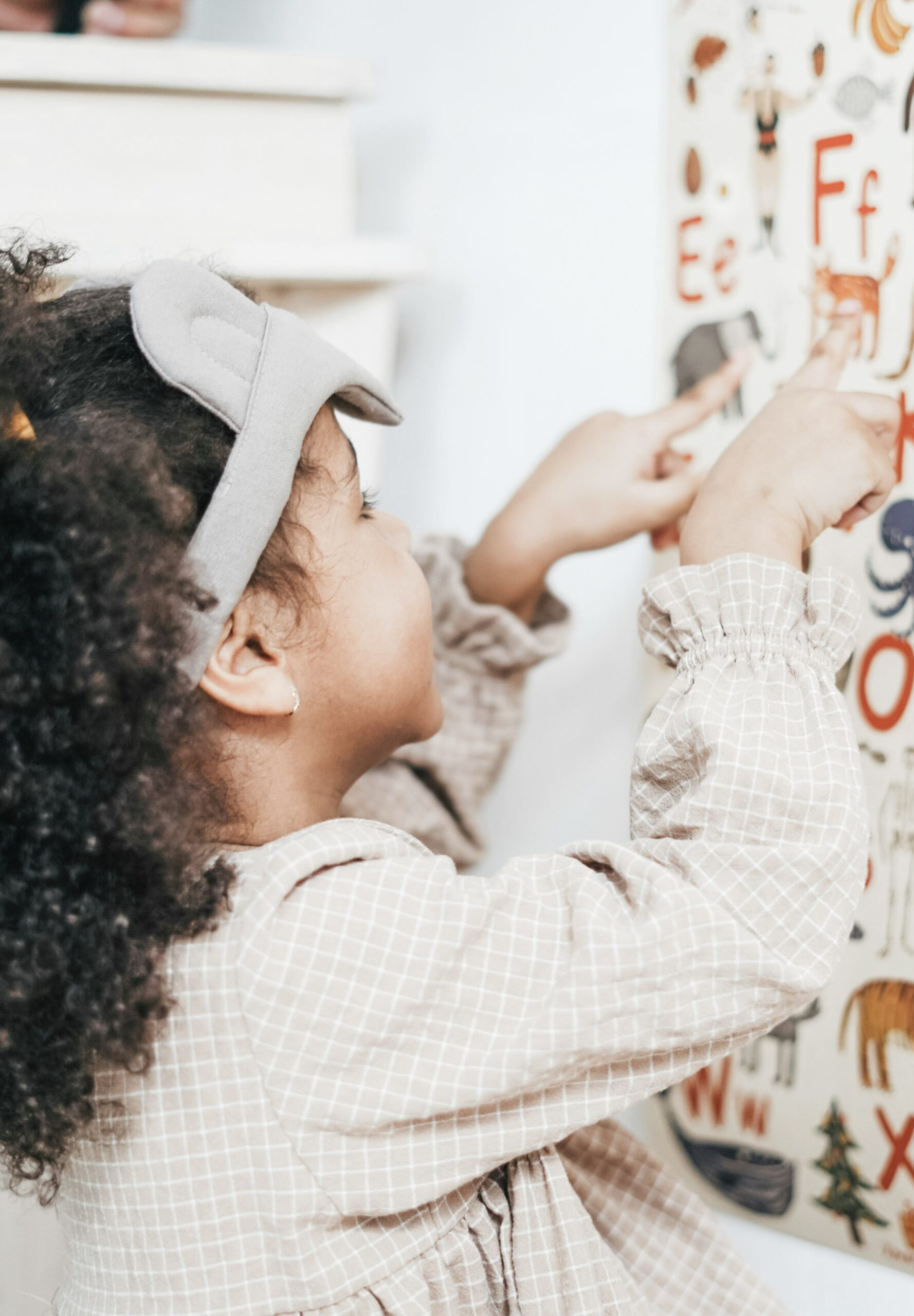 A little girl looks at an alphabet on the wall. This article covers how preschool readiness shapes future learning.