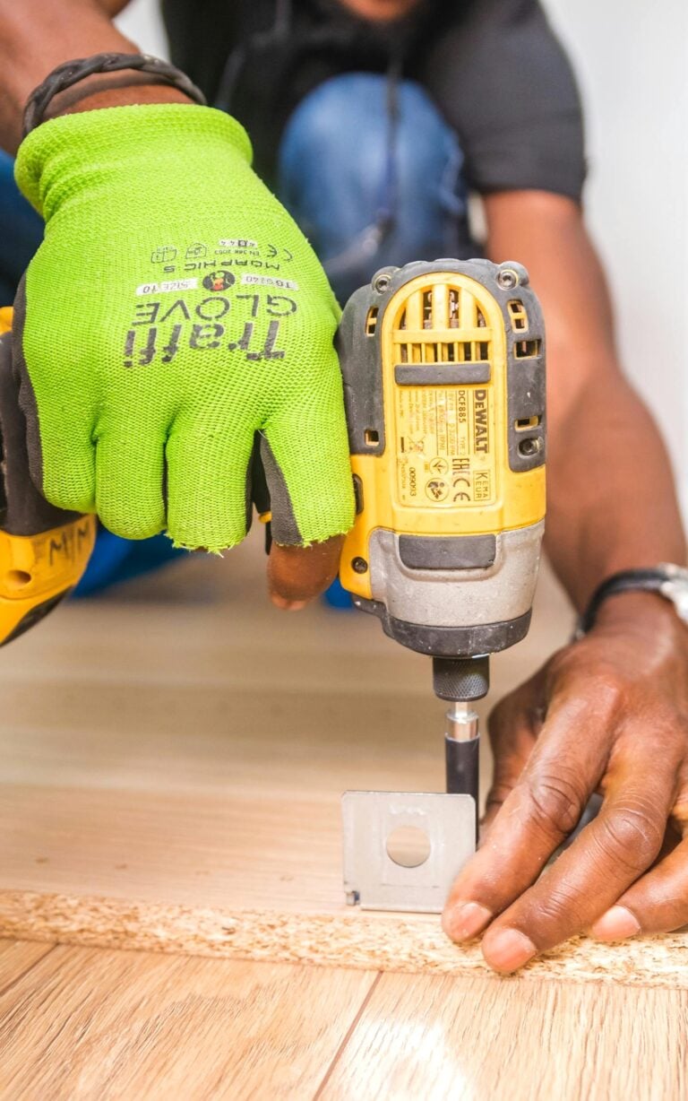 Man using a Dewalt tool attaching a hinge to a piece of wood. This article covers key areas of your home that deserve a quick checkup today.