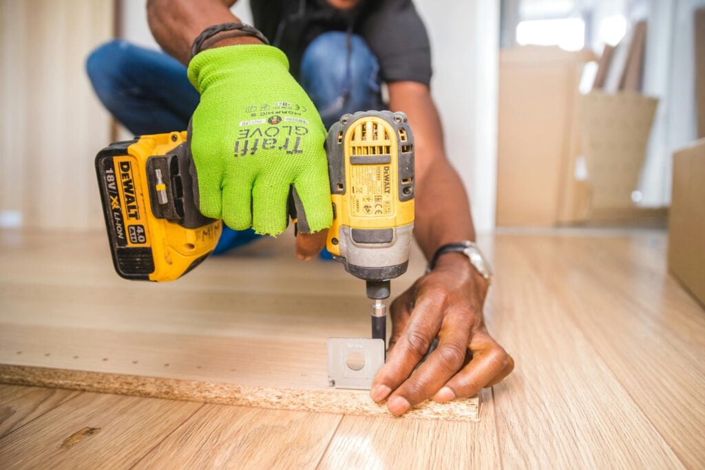 Man using a Dewalt tool attaching a hinge to a piece of wood. This article covers key areas of your home that deserve a quick checkup today.