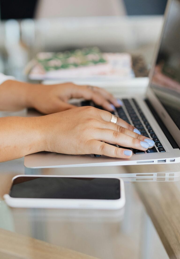 Person typing on laptop, there is a phone next to it. This article covers starting your first business.