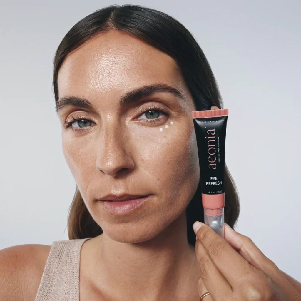 A woman holds up aeonia Eye Refresh and shows where the serum should be placed. 