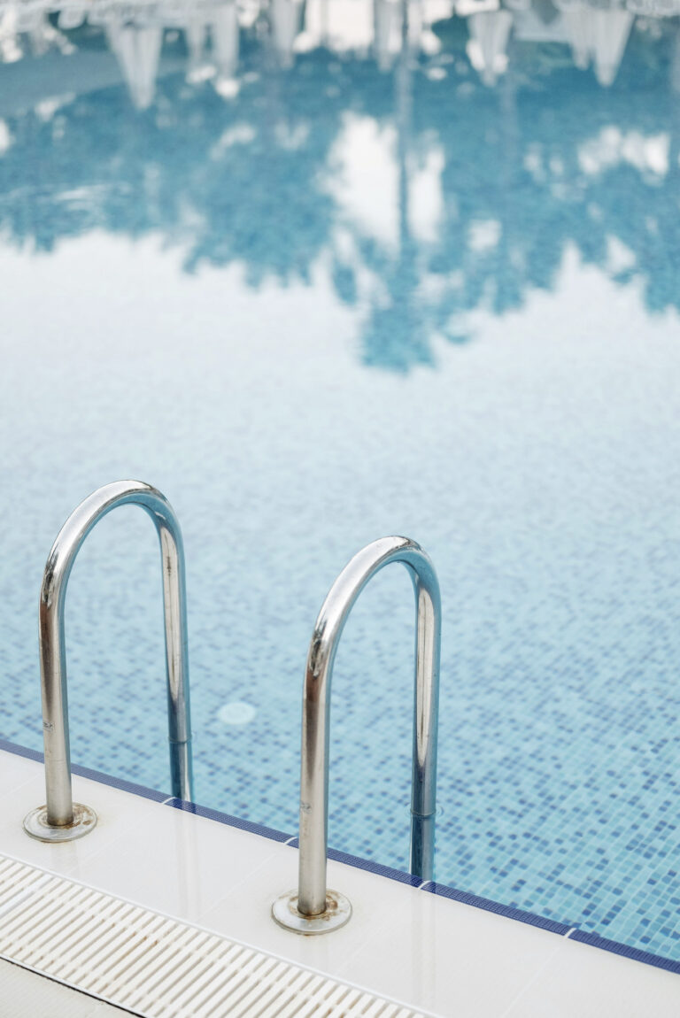 A still pool and pool ladder are shown. This article covers smart tips for planning a new pool area.