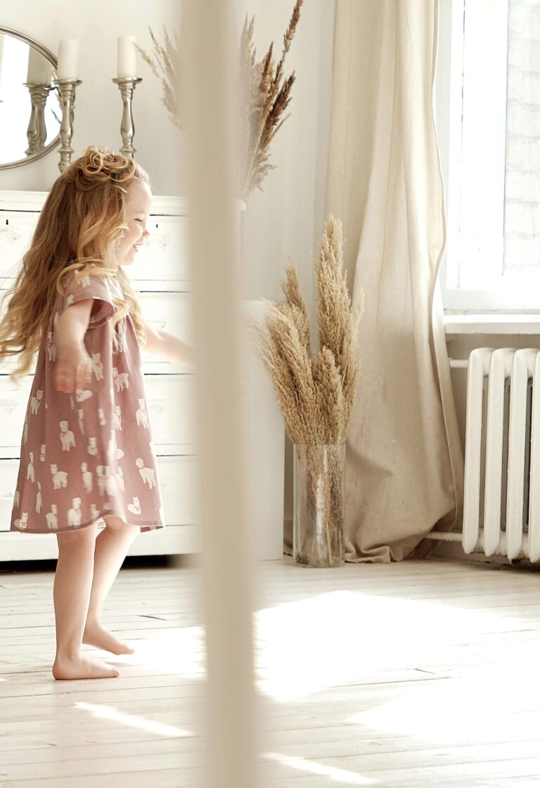 Woman walks behind a little girl, in the room, there is a water heater. This article covers how to save on utilities and efficient hot water systems for homes.