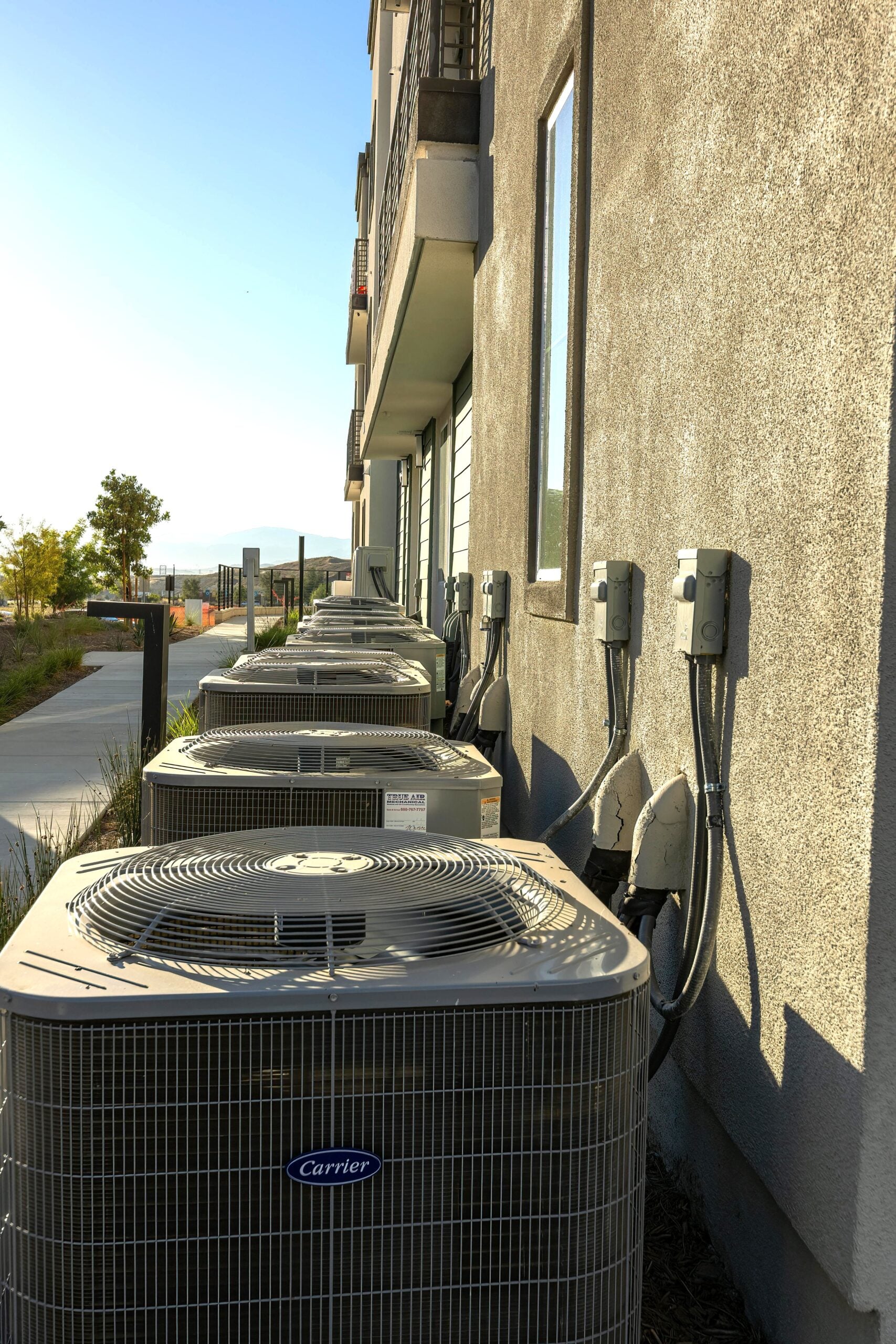 Air Conditioners attached to the back of a building. This article covers how regular HVAC maintenance can improve comfort and cut costs.