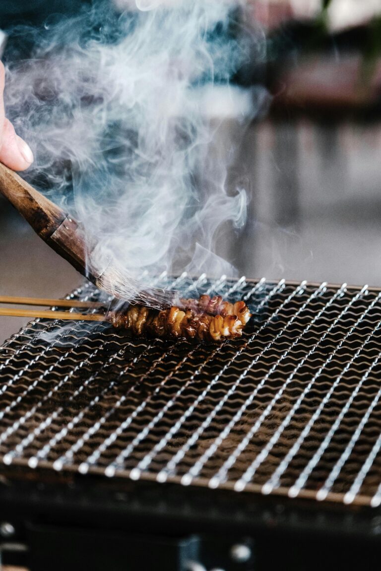 Close-up of a delicious grilled yakitori skewer cooking on a smoking grill.