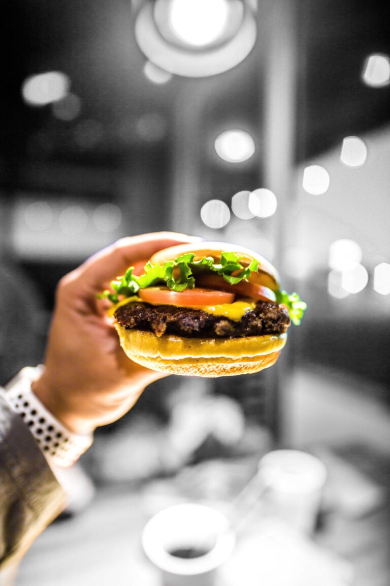 A man wearing a business suit holds a fresh burger. This article covers why fresh burgers are the ideal airport meal in Mississauga.