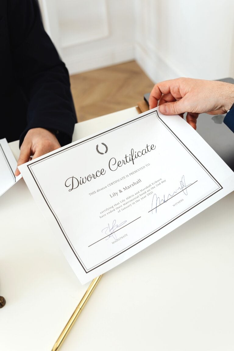 A hand holds a signed divorce decree, and a gold pen rests on the same table. This article answers the question, are divorce records confidential?