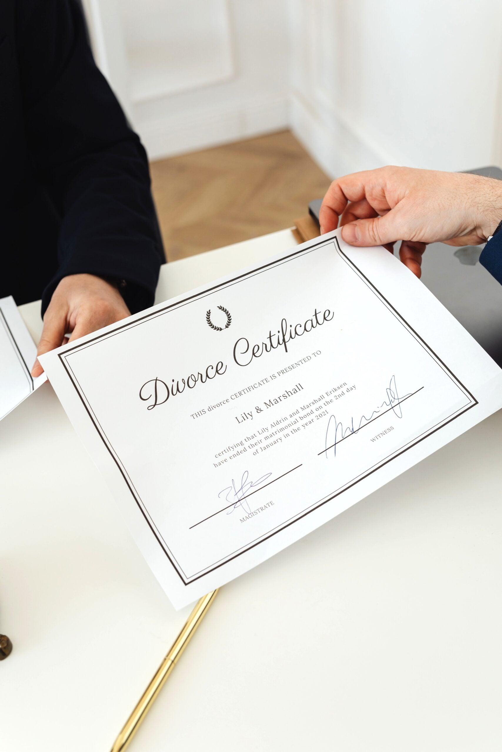 A hand holds a signed divorce decree, and a gold pen rests on the same table. This article answers the question, are divorce records confidential?