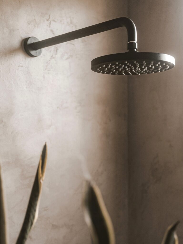 A close up of a modern rain shower fixture in a warm tiled bathroom. This article shares top shower renovation trends for a luxurious spa-like bathroom.