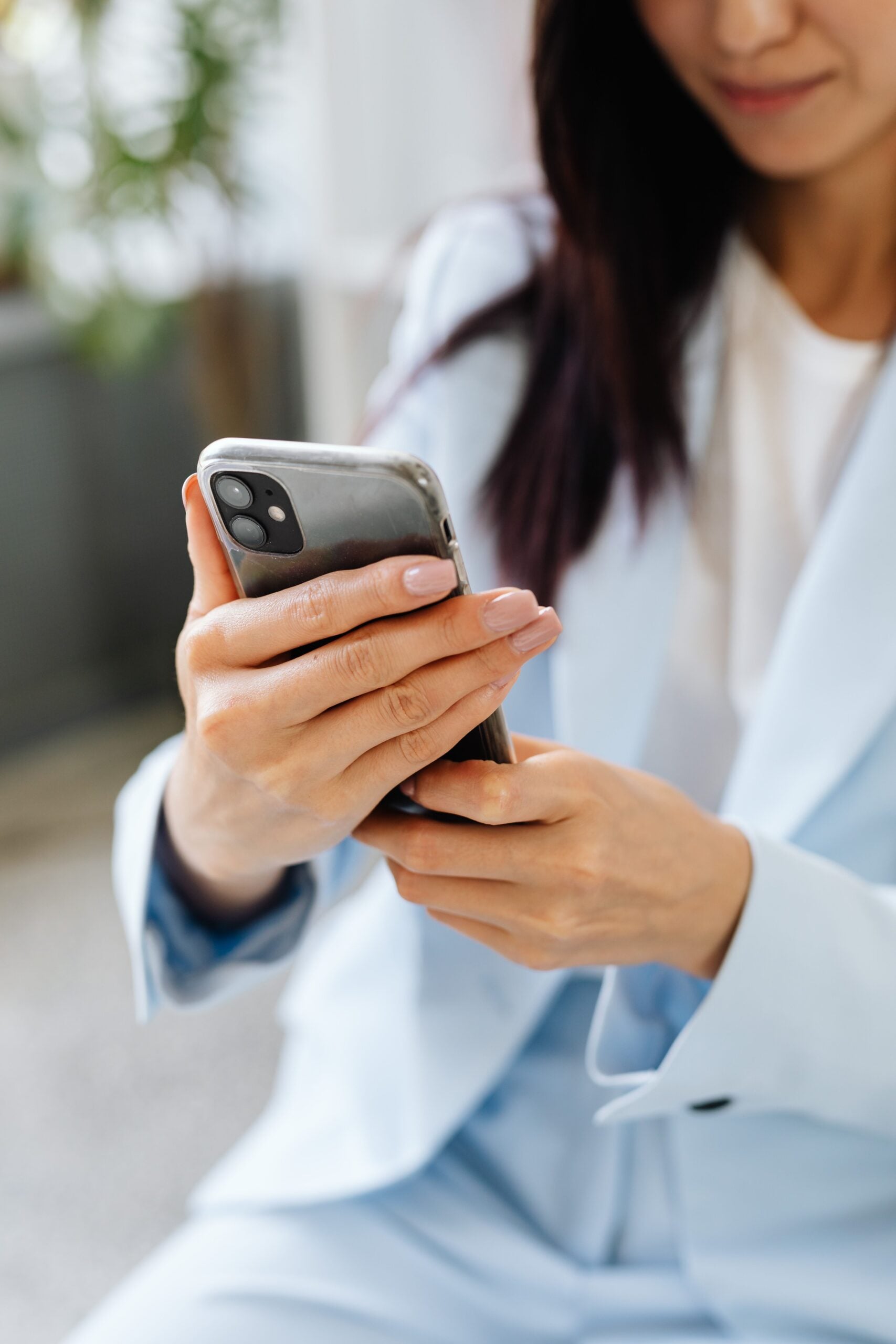 Woman holds phone and smiles. This article describes how to safely download and use money-making apps.