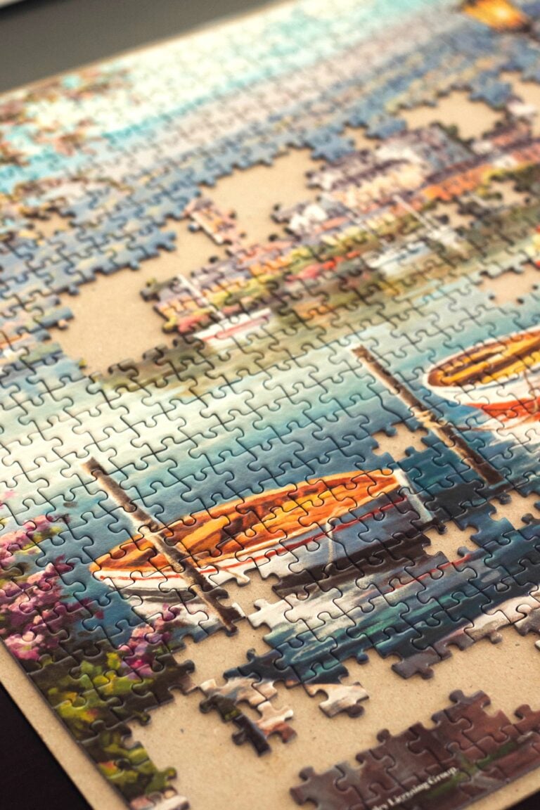 An almost finished puzzle of a ship and seascape is shown. This article answers why hobbyists are choosing artistic jigsaw puzzles and illustrated designs.