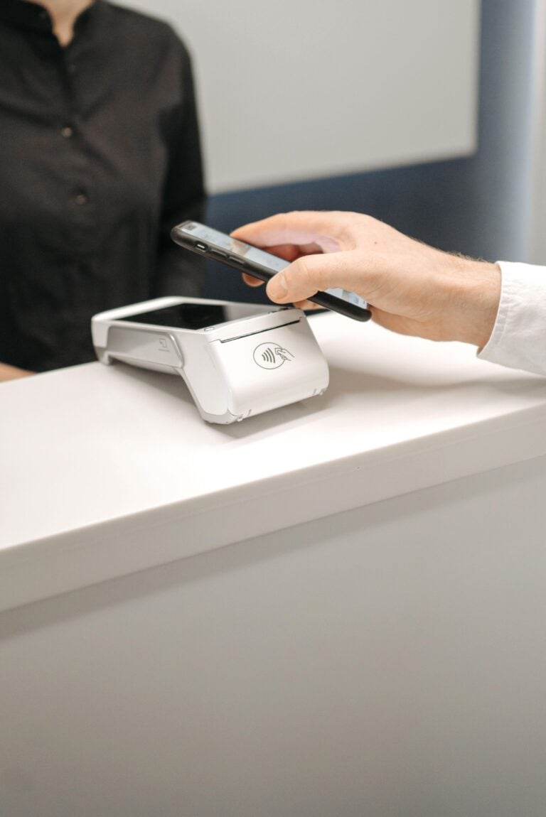 Person using a smartphone for contactless payment at a retail counter, highlighting cashless convenience. This article covers better banking habits