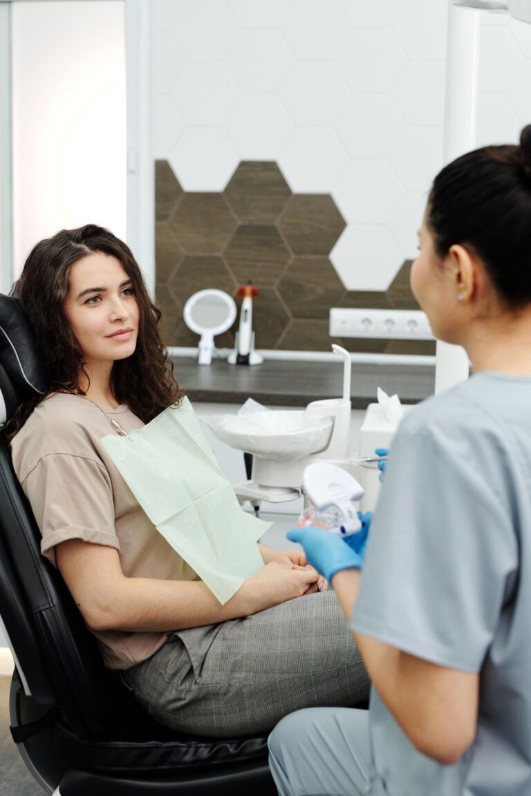 A dental assistant sits and speaks to a patient at a dentist's office. This article covers modern trends in family dental care.