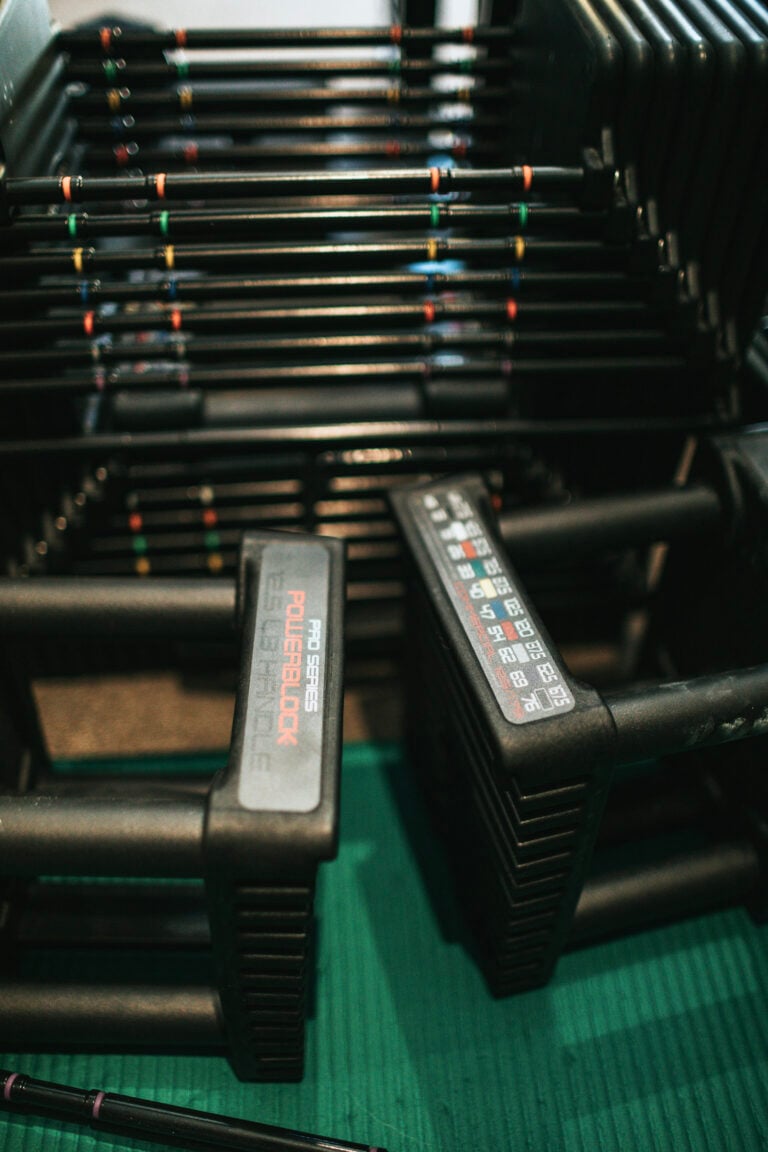A stack of adjustable dumbbells are shown stacked, this article describes why adjustable dumbbells are perfect for busy lifestyles.