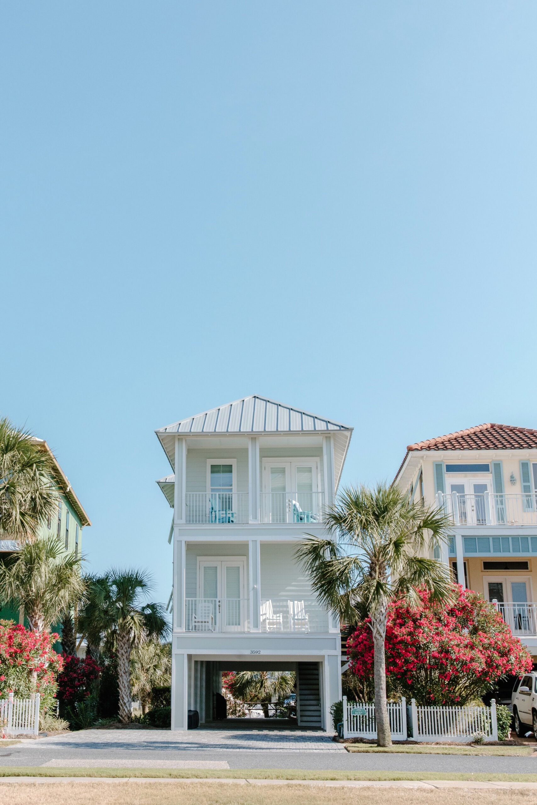 A beautiful tropical house surrounded by palm trees and vibrant flowers. This article helps you how to decide if a vacation town is the right place to buy a home.