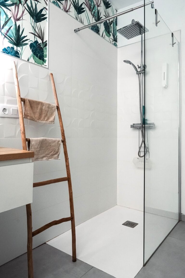 A walk-in shower with white tile and a ladder to hold towels. This article covers how to transform your bathroom with a walk-in shower remodel.