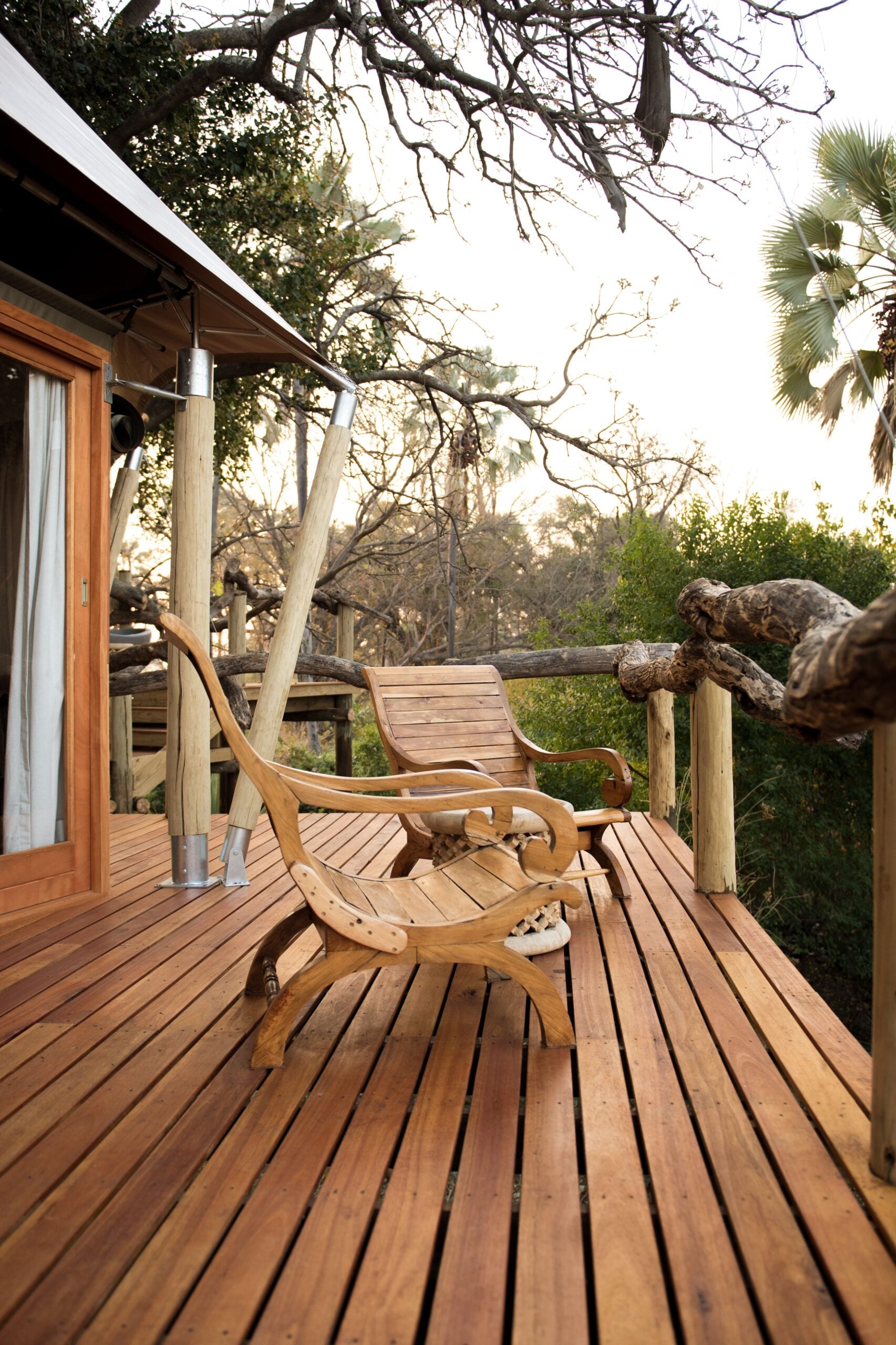 Two wooden chairs on a rustic deck surrounded by lush nature. This article shares how to plan a custom deck that fits your yard and lifestyle.