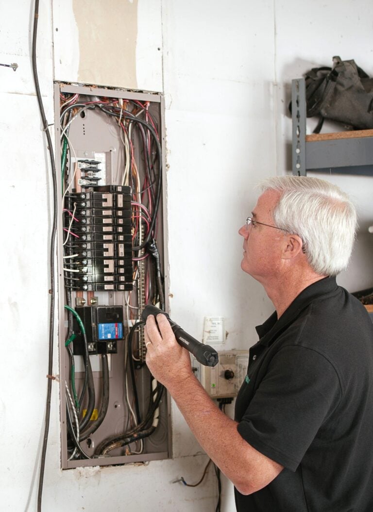 An electrician carefully examines a residential fuse box indoors, ensuring electrical safety and compliance. This article covers how to integrate residential electrical installations in neighborhoods.