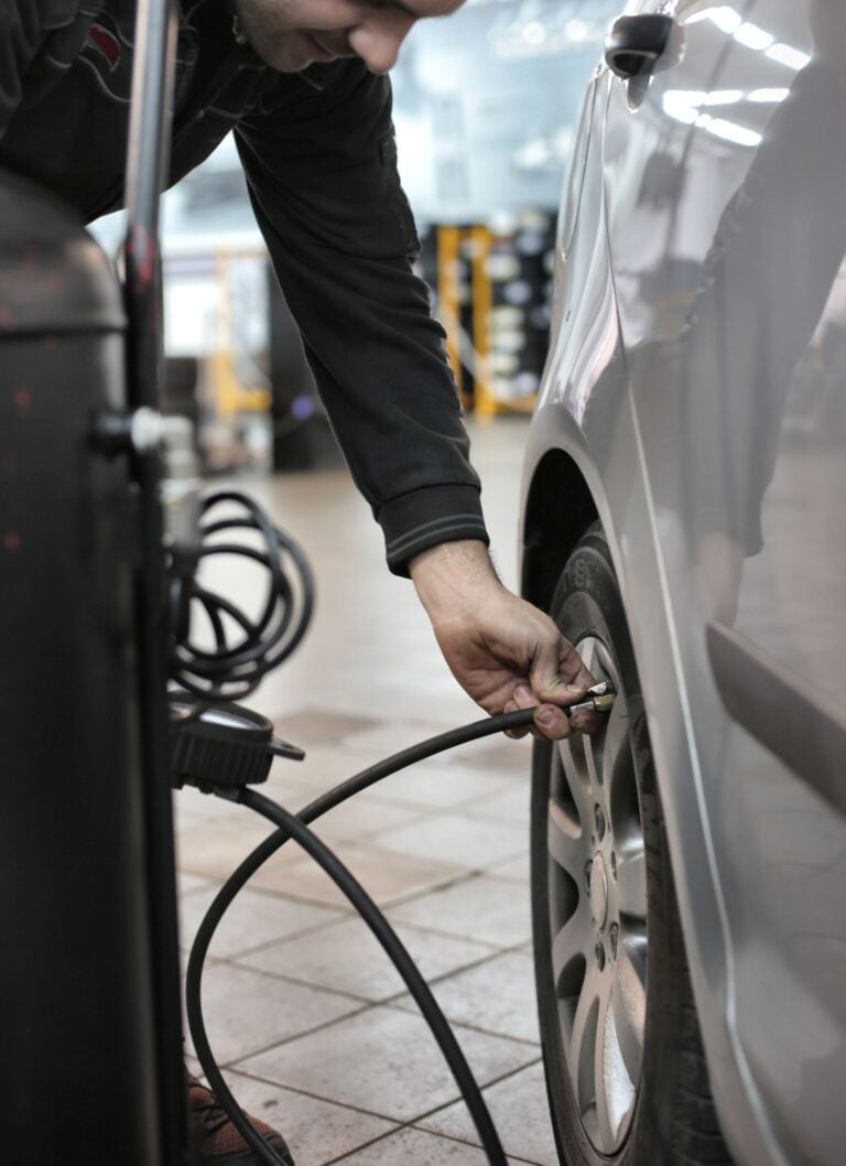 Mechanic adjusting tire pressure of a vehicle in an indoor automotive service center. This article shares a car maintenance checklist that is useful for every car owner.