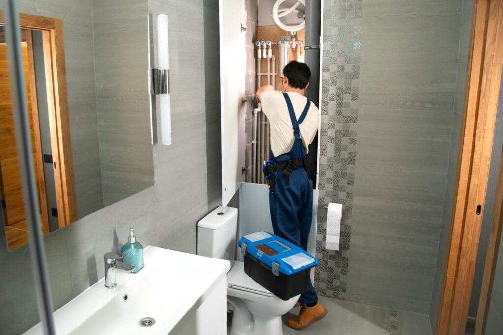 A plumber works on piping in a modern bathroom This article shares everything you need to know before hiring a plumber.