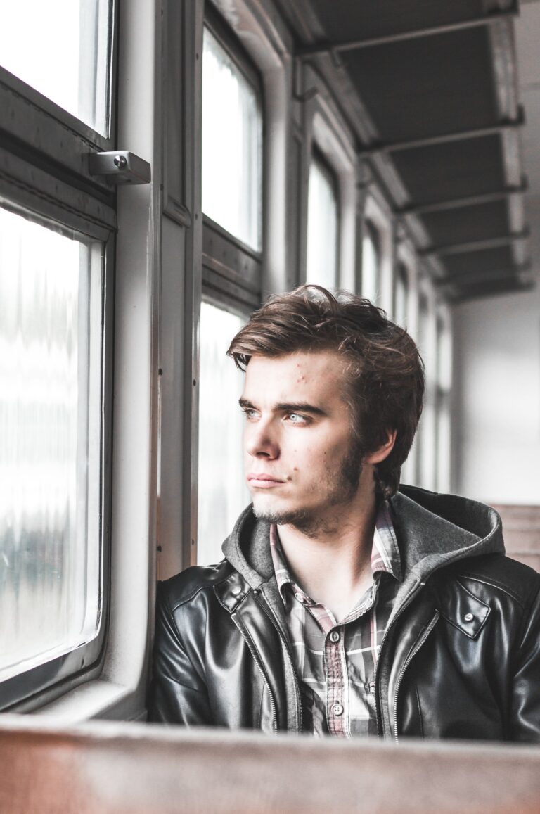 Man in a leather jacket gazing out a train window, deep in thought. This article shares how a DUI charge can quietly disrupt everyday life.