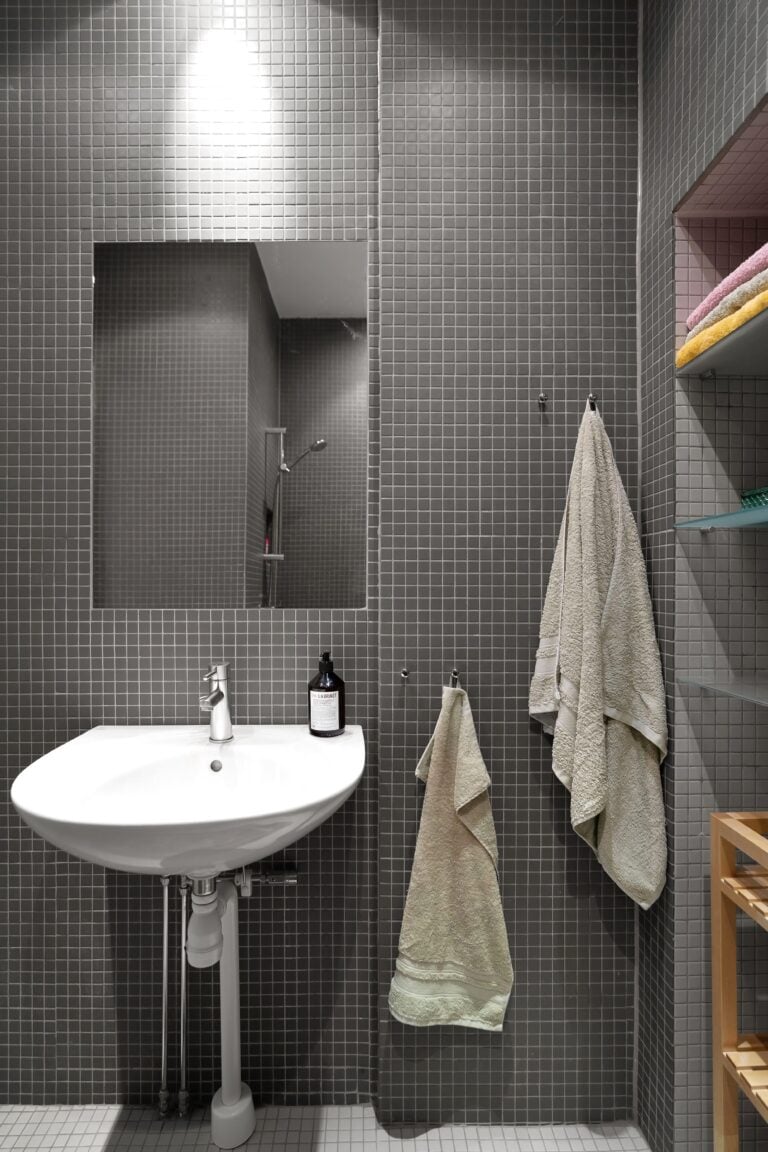 Elegant minimalist bathroom featuring a sink, mirror, and gray tiles. This article covers critical considerations for homeowners if you're adding a second bathroom.