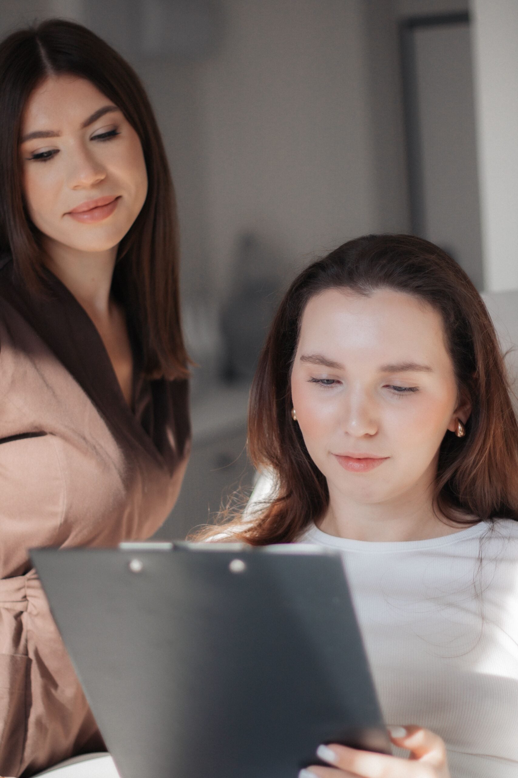 Two women reviewing documents together in a bright indoor setting. This article discusses how small businesses can offer cost-effective dental benefits.