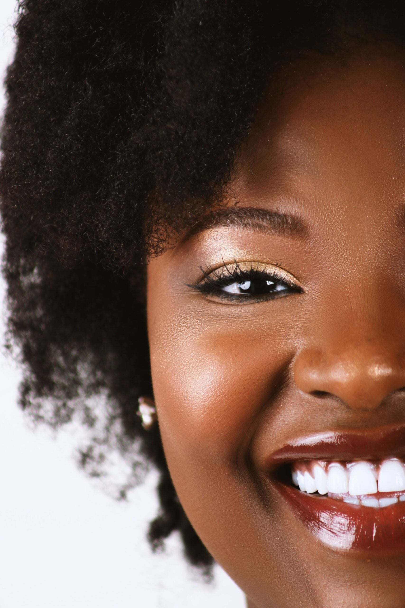 Vibrant portrait of a smiling woman with natural hair and radiant features. This article shares how to choose the right teeth whitening method for your smile.