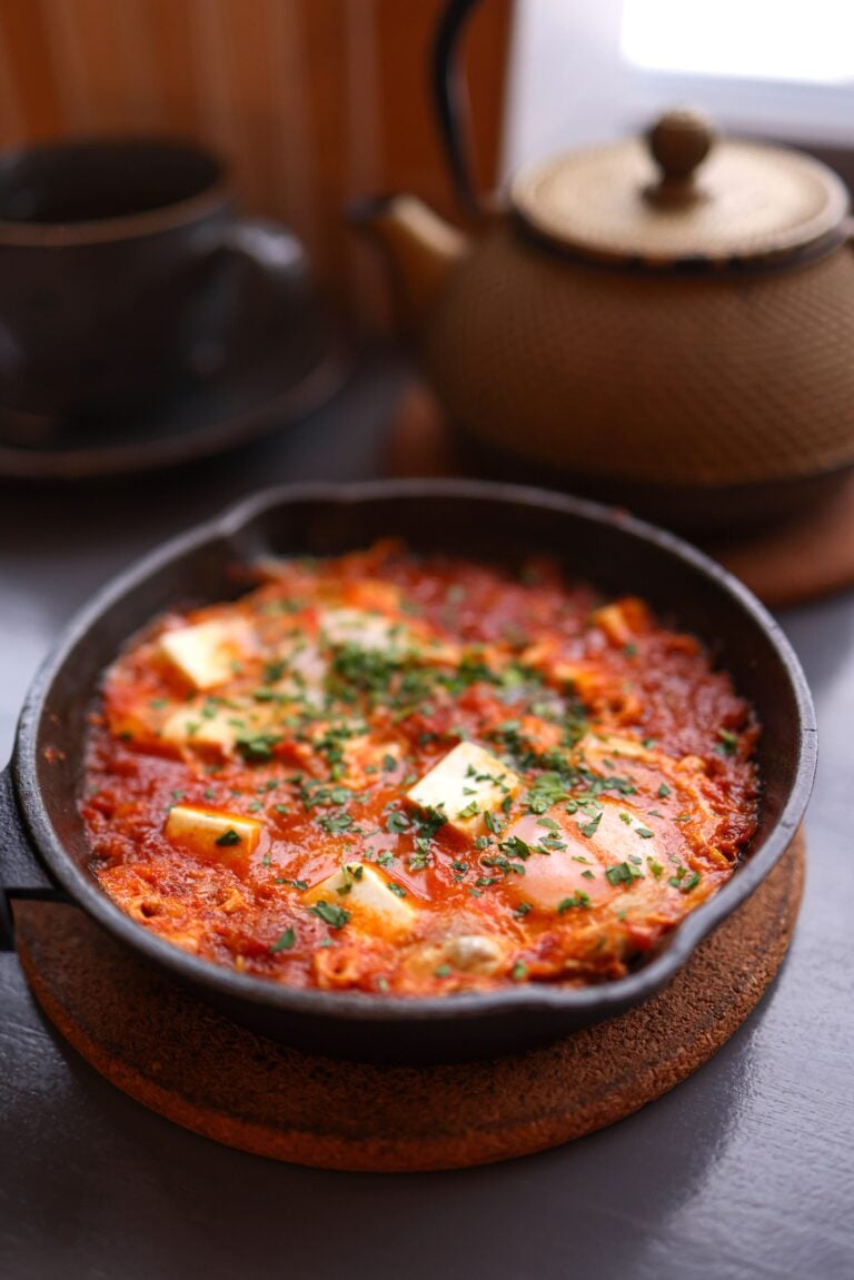 Delicious shakshuka with melted cheese and herbs in a cozy setting. This article shares about understanding comfort food, the warmth, texture, and the pull of familiar flavors.