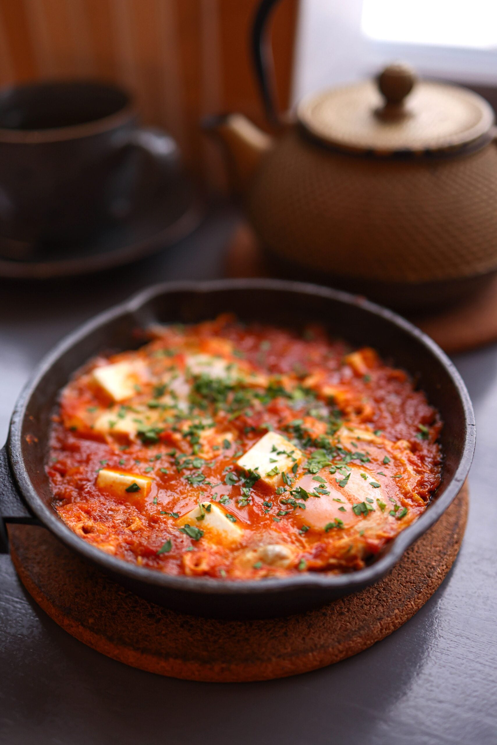 Delicious shakshuka with melted cheese and herbs in a cozy setting. This article shares about understanding comfort food, the warmth, texture, and the pull of familiar flavors.