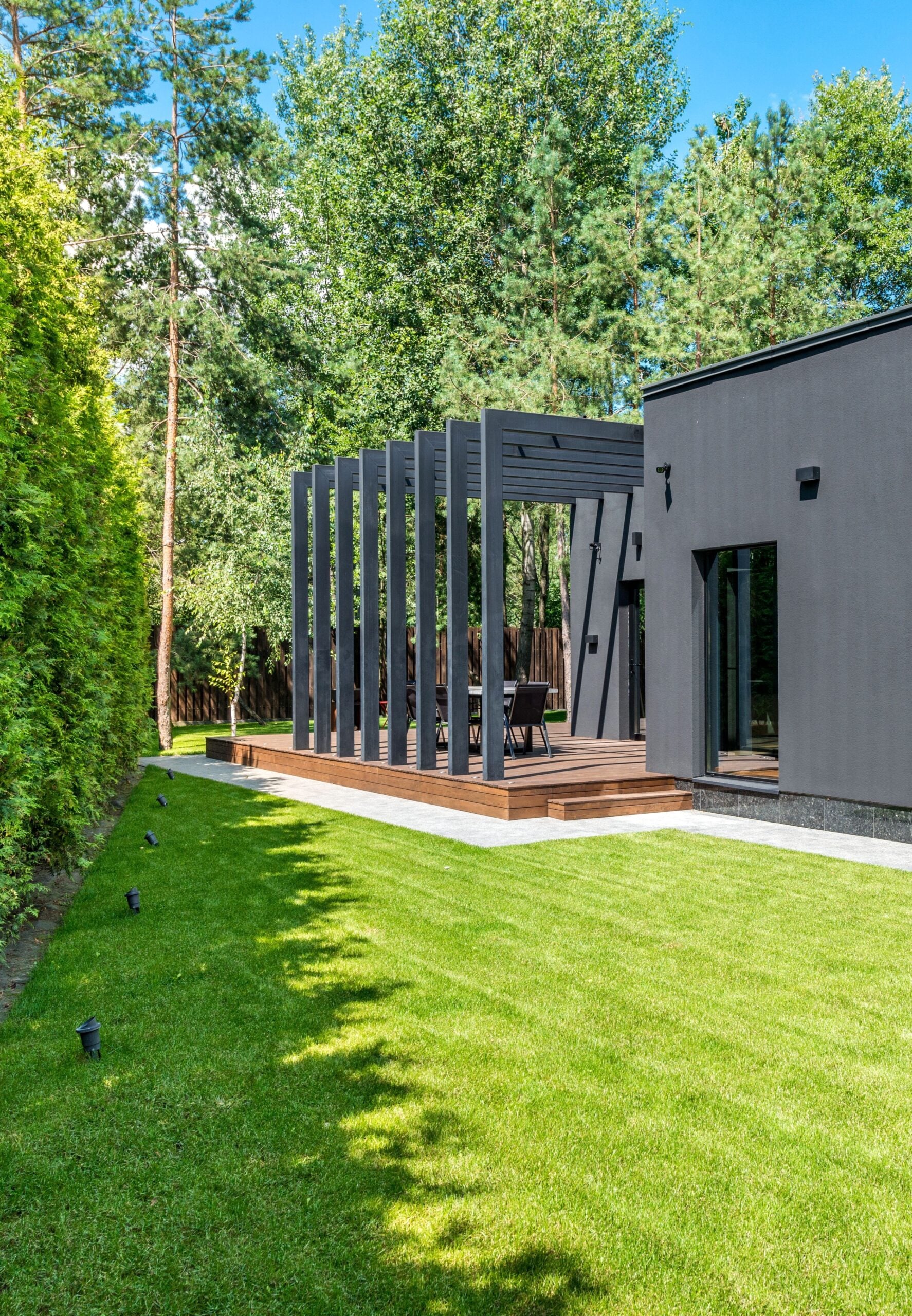 Contemporary house exterior with spacious lawn and pergola, set in a serene outdoor environment. This article covers what to consider when updating your home's exterior.