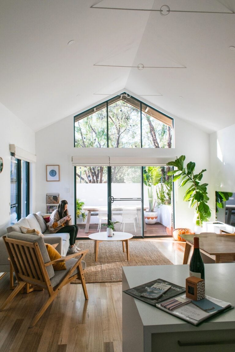 Spacious modern living room with lush plants and natural light, perfect for relaxation. This article shares a room-by-room guide to preparing your rental for inspection.