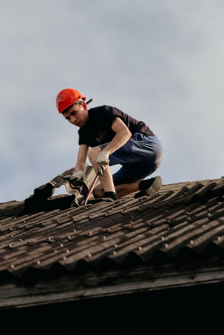 A construction worker with a safety helmet is repairing a roof outdoors during the day. This article shares what to expect when hiring a roofing company.