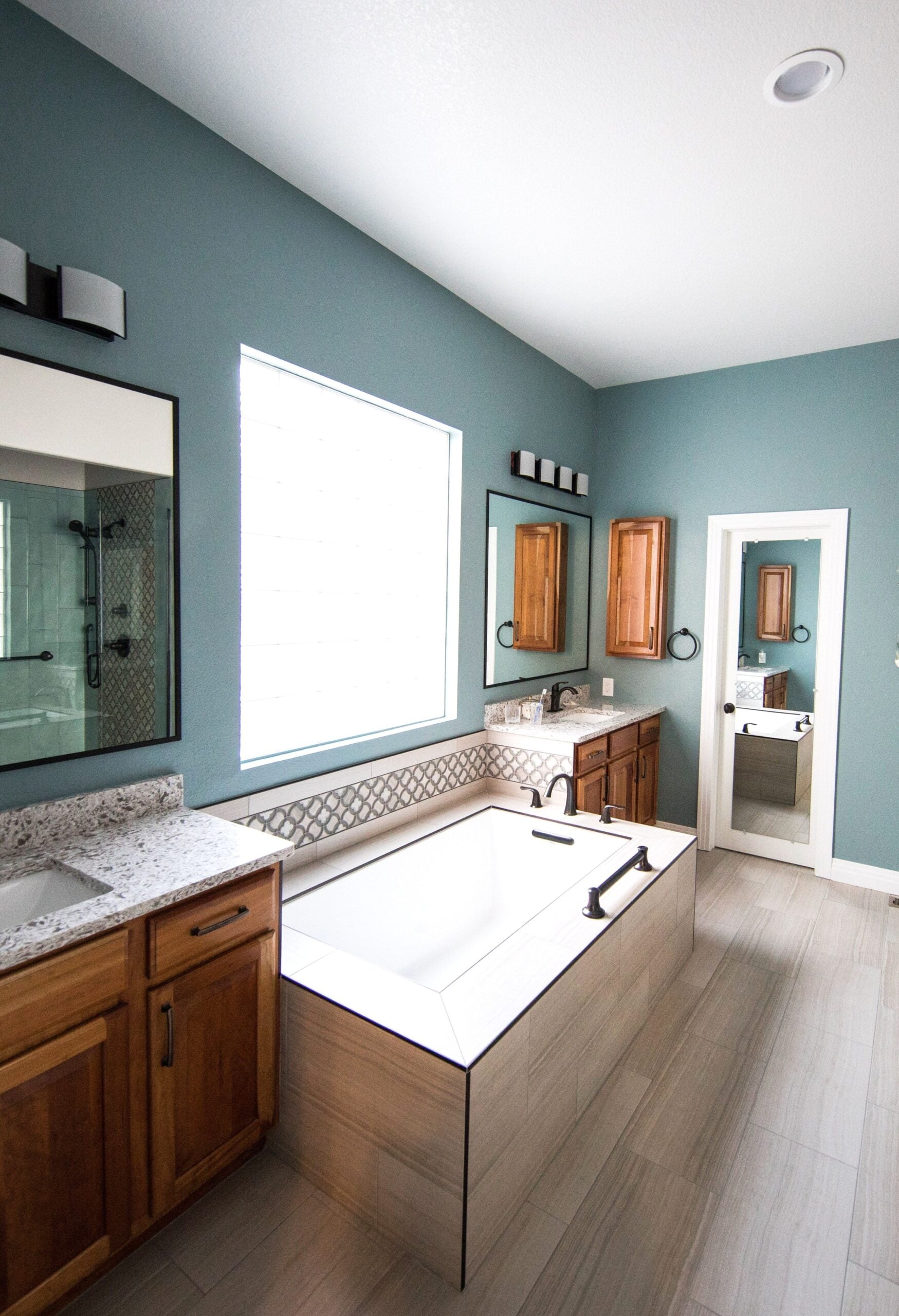 Spacious modern bathroom featuring a freestanding bathtub, wooden cabinets, and granite countertops. This shares what truly works when planning a bathroom for your home.