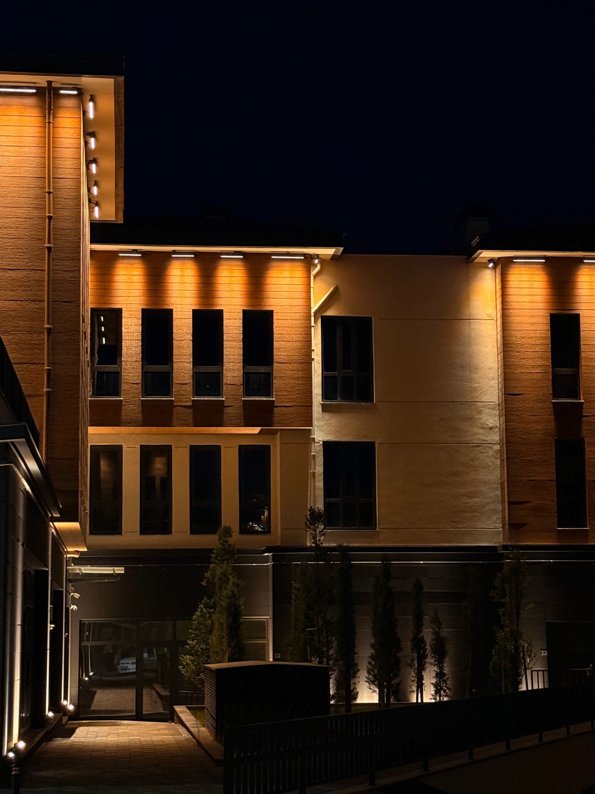 A contemporary building facade illuminated with warm lights against a night sky. This article shares top outdoor lighting choices for Omaha homeowners.